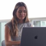 A woman focusing on her laptop, studying in an outdoor setting.