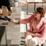 Smiling woman in wheelchair using smartphone for payment at cafe.