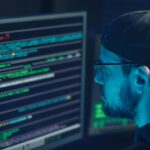 A cybersecurity expert inspecting lines of code on multiple monitors in a dimly lit office.
